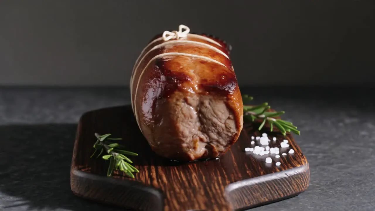 Rôti de bœuf ficelé, doré, sur sa planche